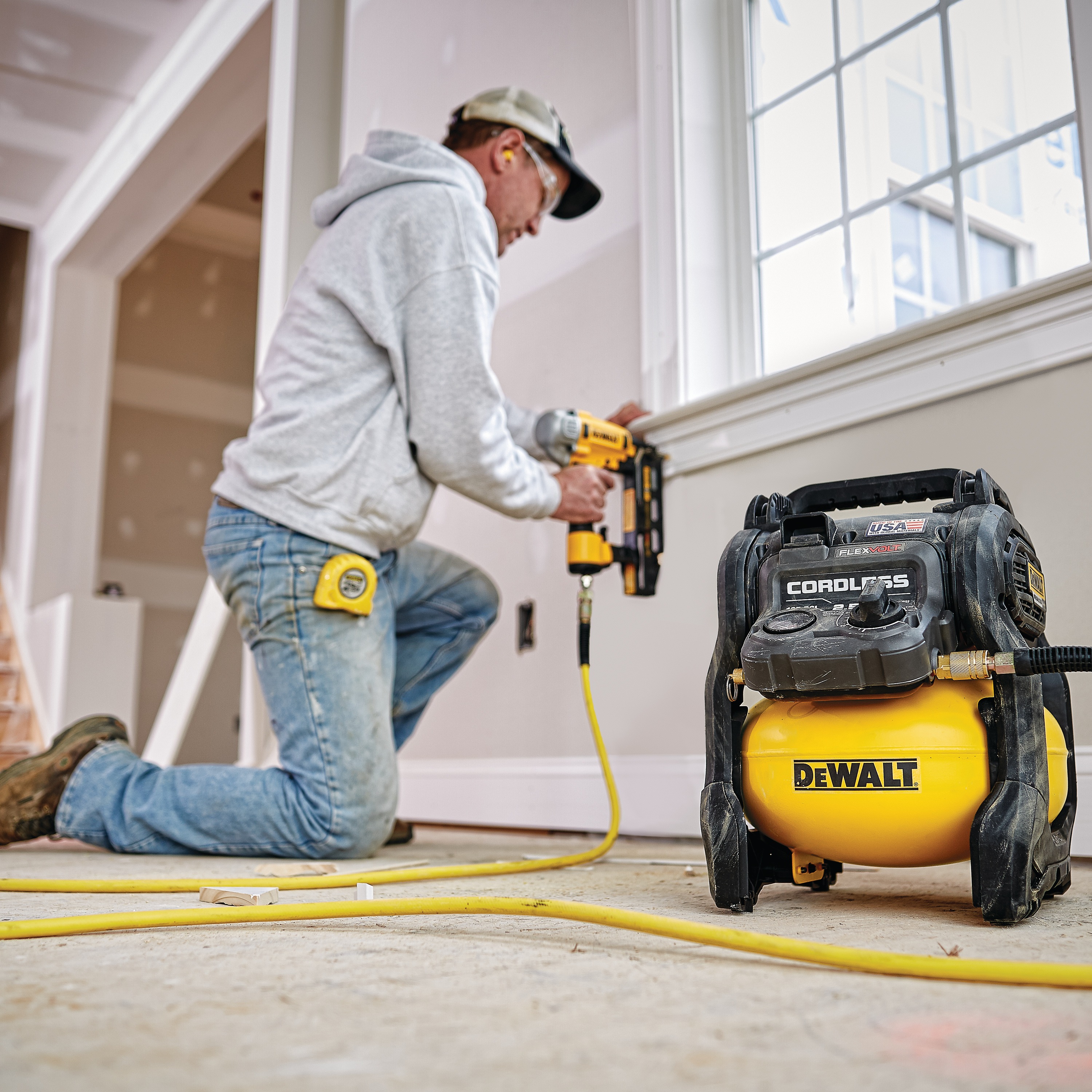FLEXVOLT® 2.5 GALLON CORDLESS AIR COMPRESSOR being used by a person to power a pneumatic nailer for countersinking holes in a wooden window frame
