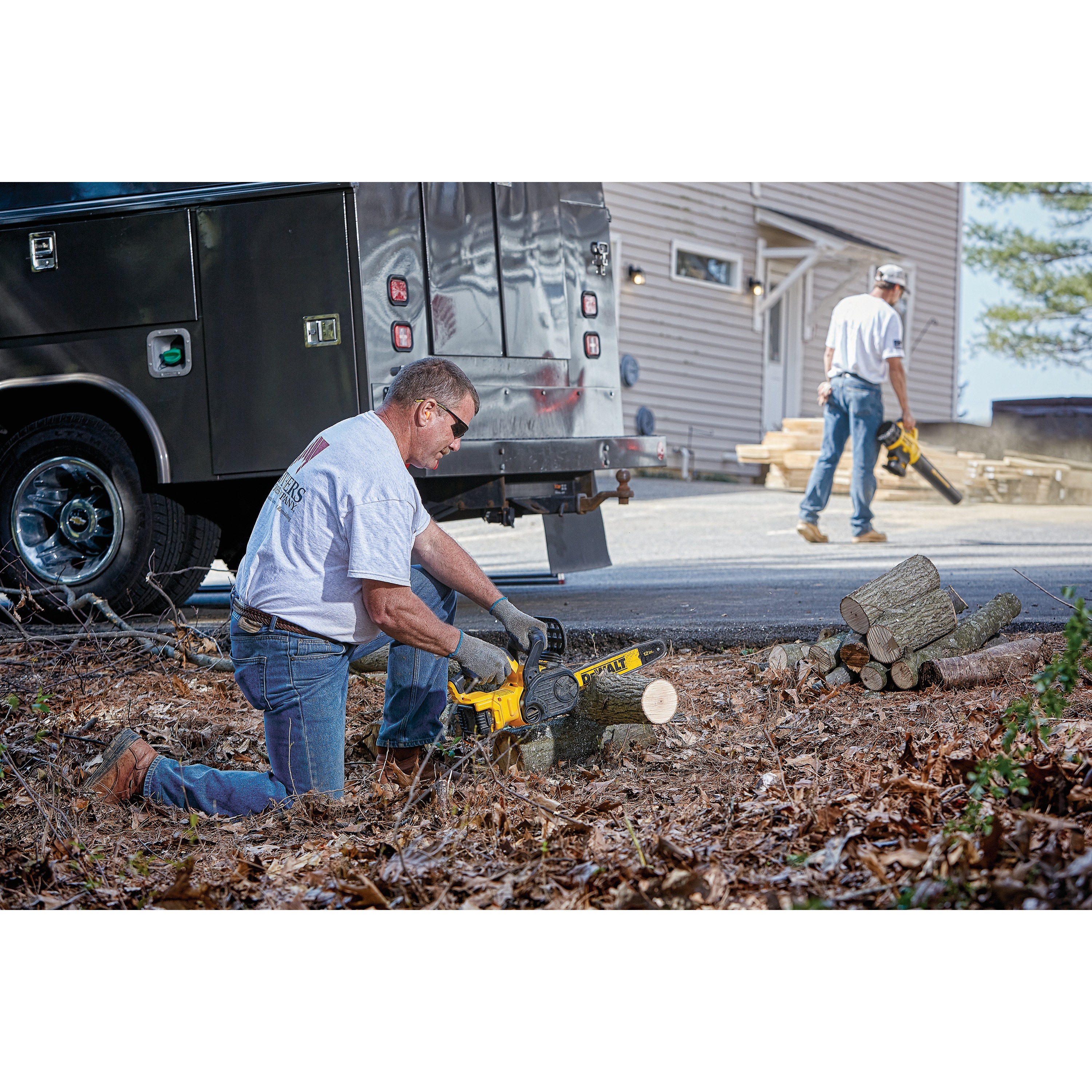XR® Compact 12 inch Cordless Chainsaw being used by a worker to cut through trimmed tree logs at worksite