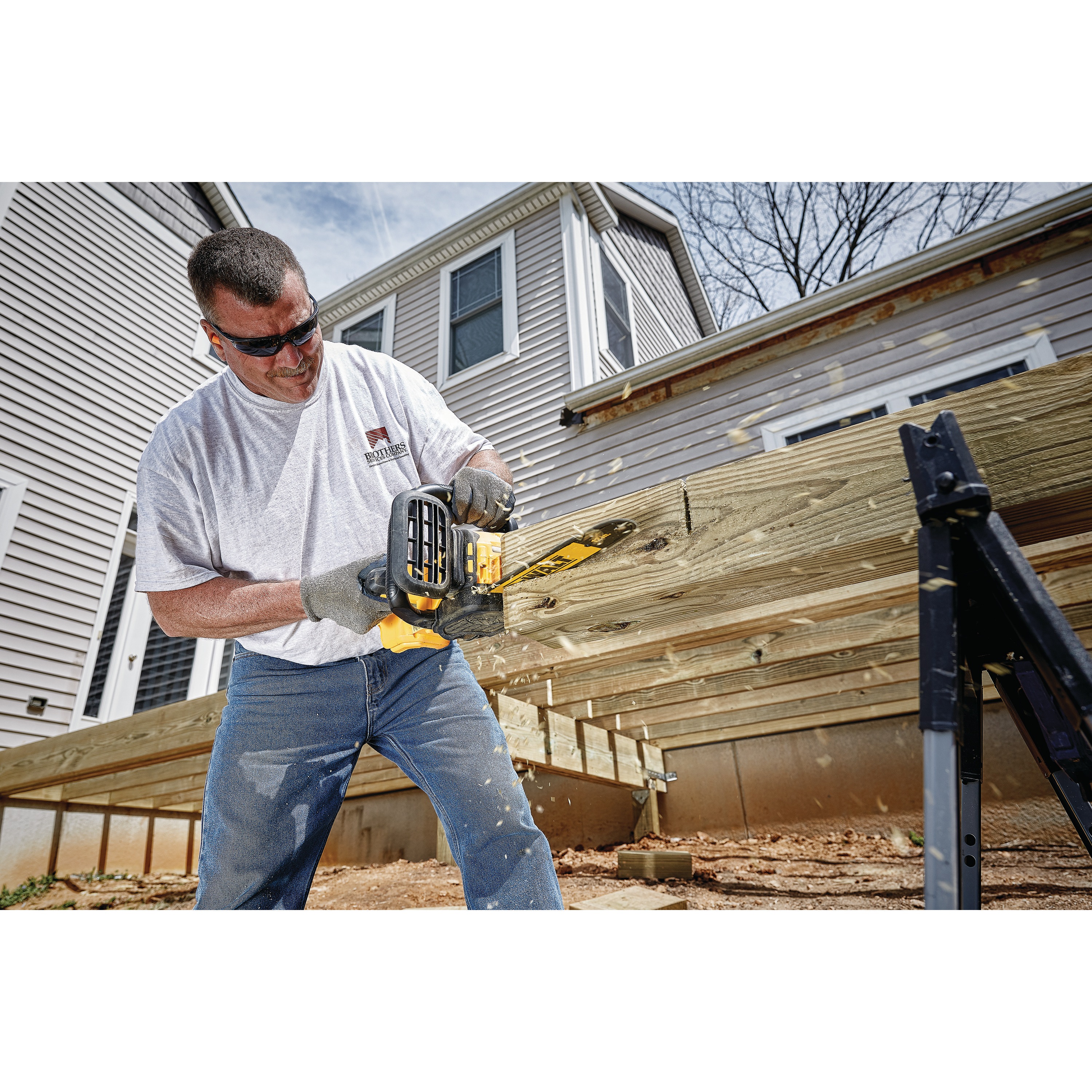 XR® Compact 12 inch Cordless Chainsaw being used by a person to cut through a square log of wood at a worksite 