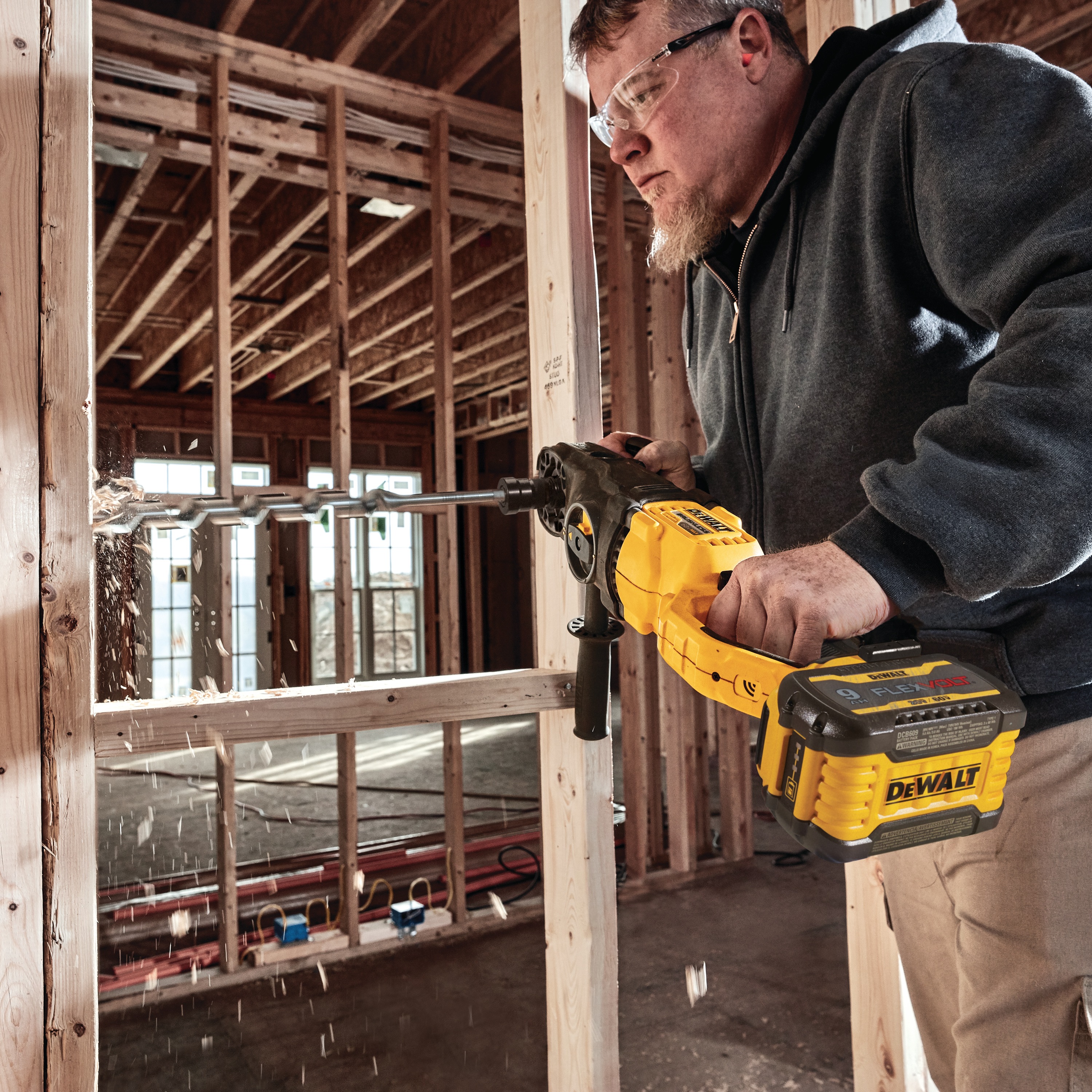 Brushless cordless quick-change stud and joist drill is being used by a person to drill  wood. 