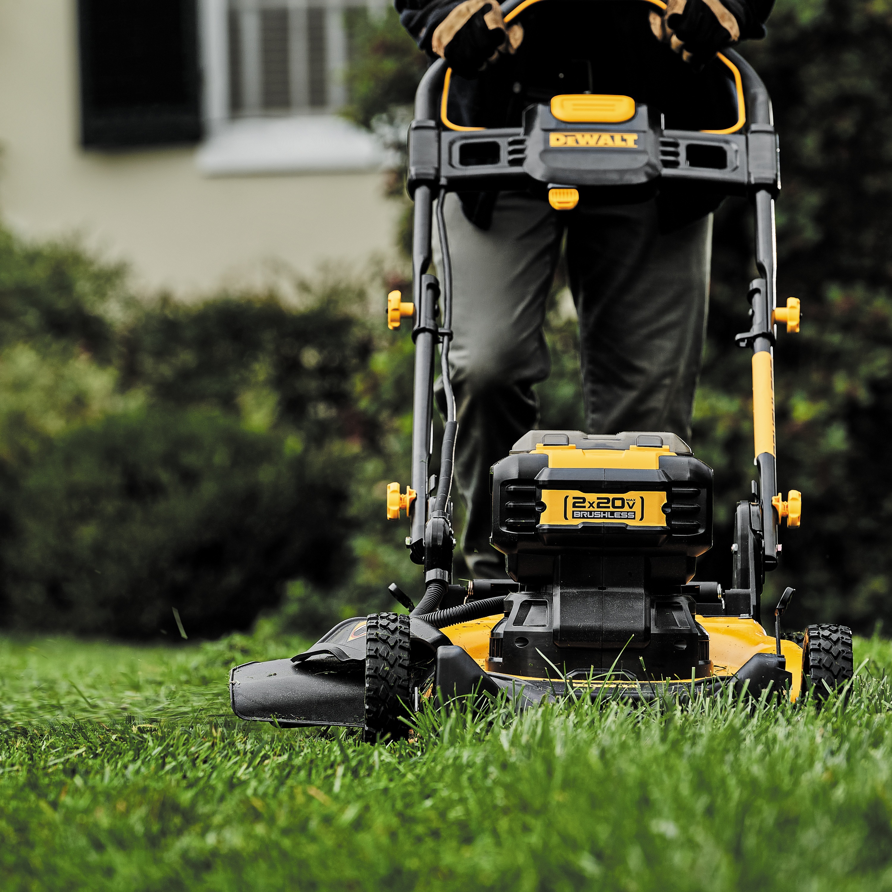 close up of brushless cordless push mower being used by a person to mow grass