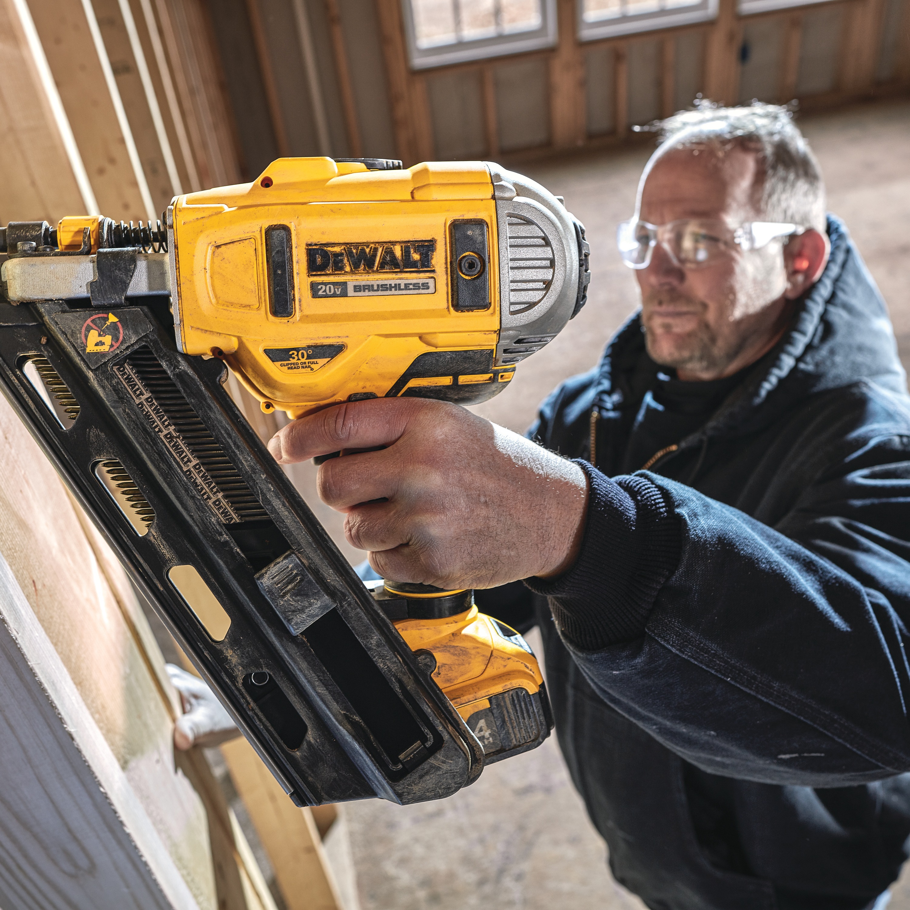 Cordless Paper Collated Framing Nailer in action on a wooden wall by a construction worker at a construction site