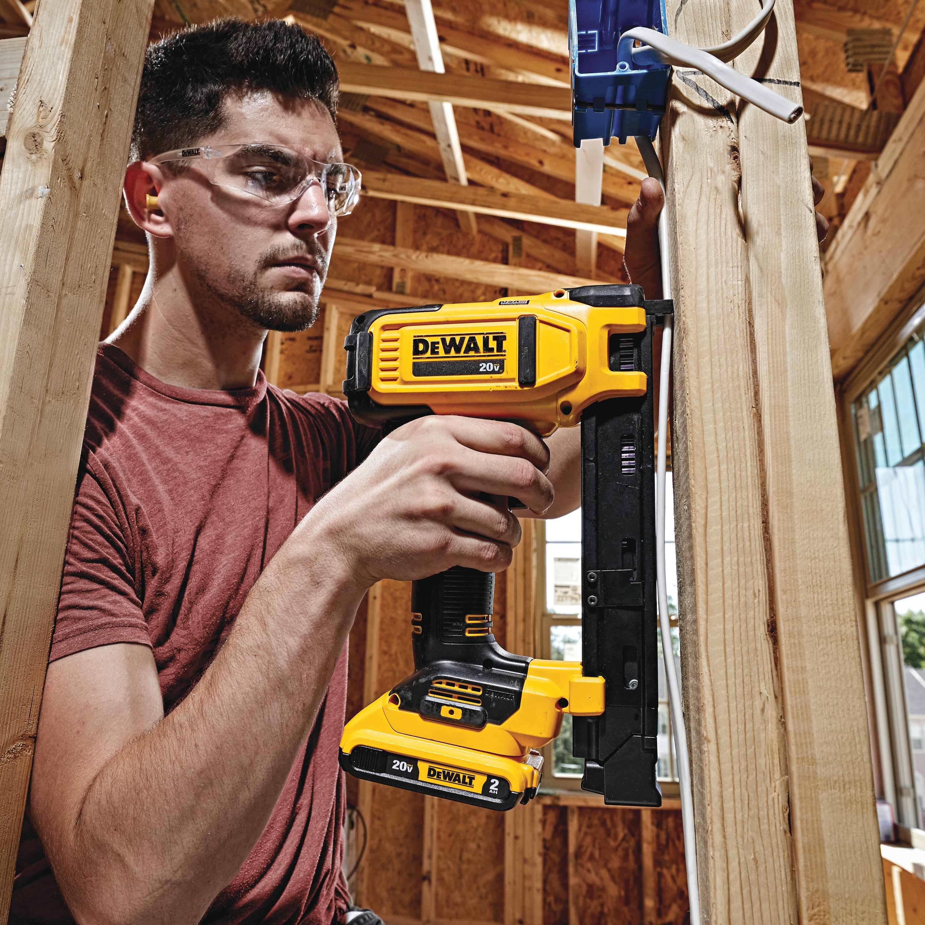 Cordless Cable Stapler in action on a wooden pillar by a construction worker at a construction site