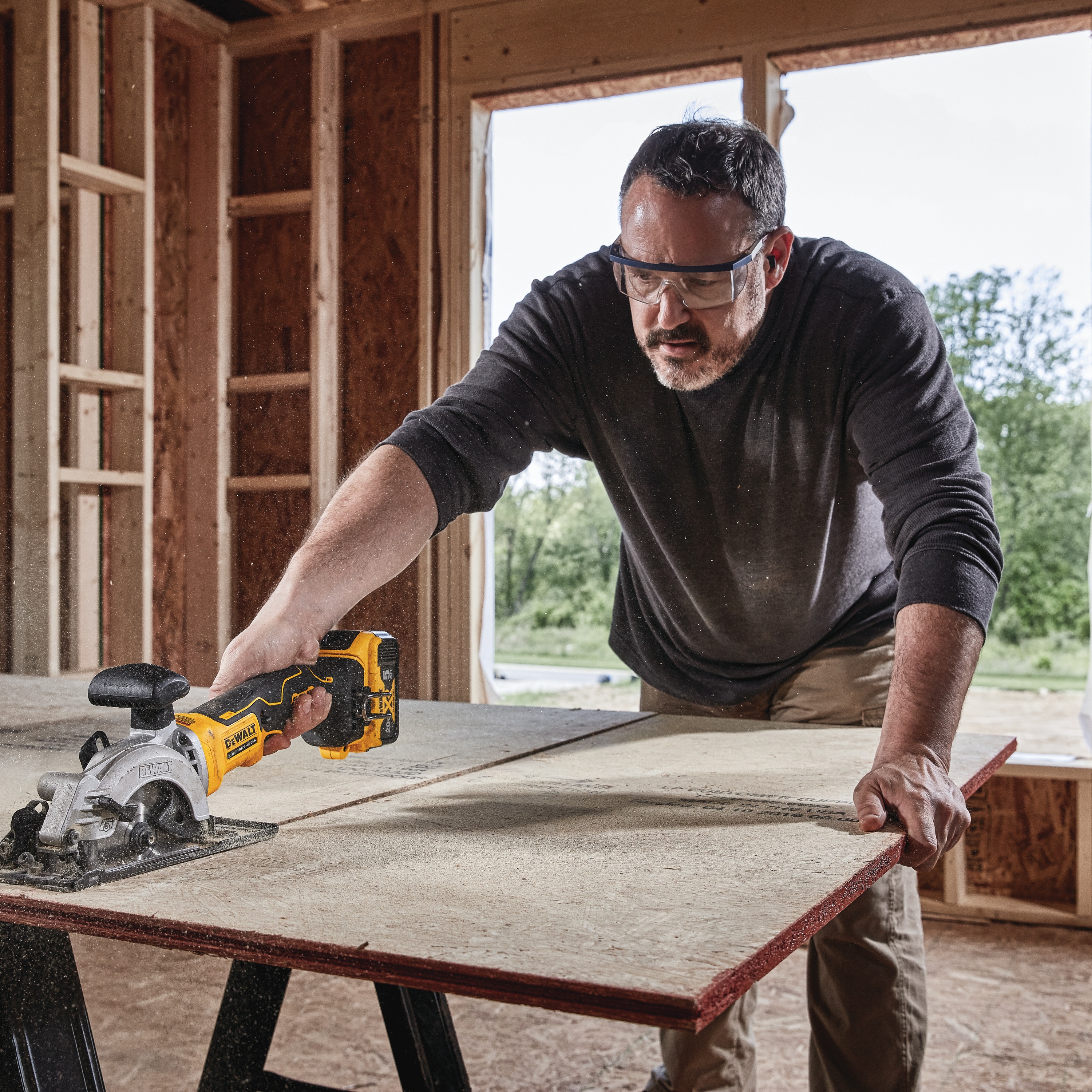 ATOMIC brushless cordless circular saw being used by person on wooden board.