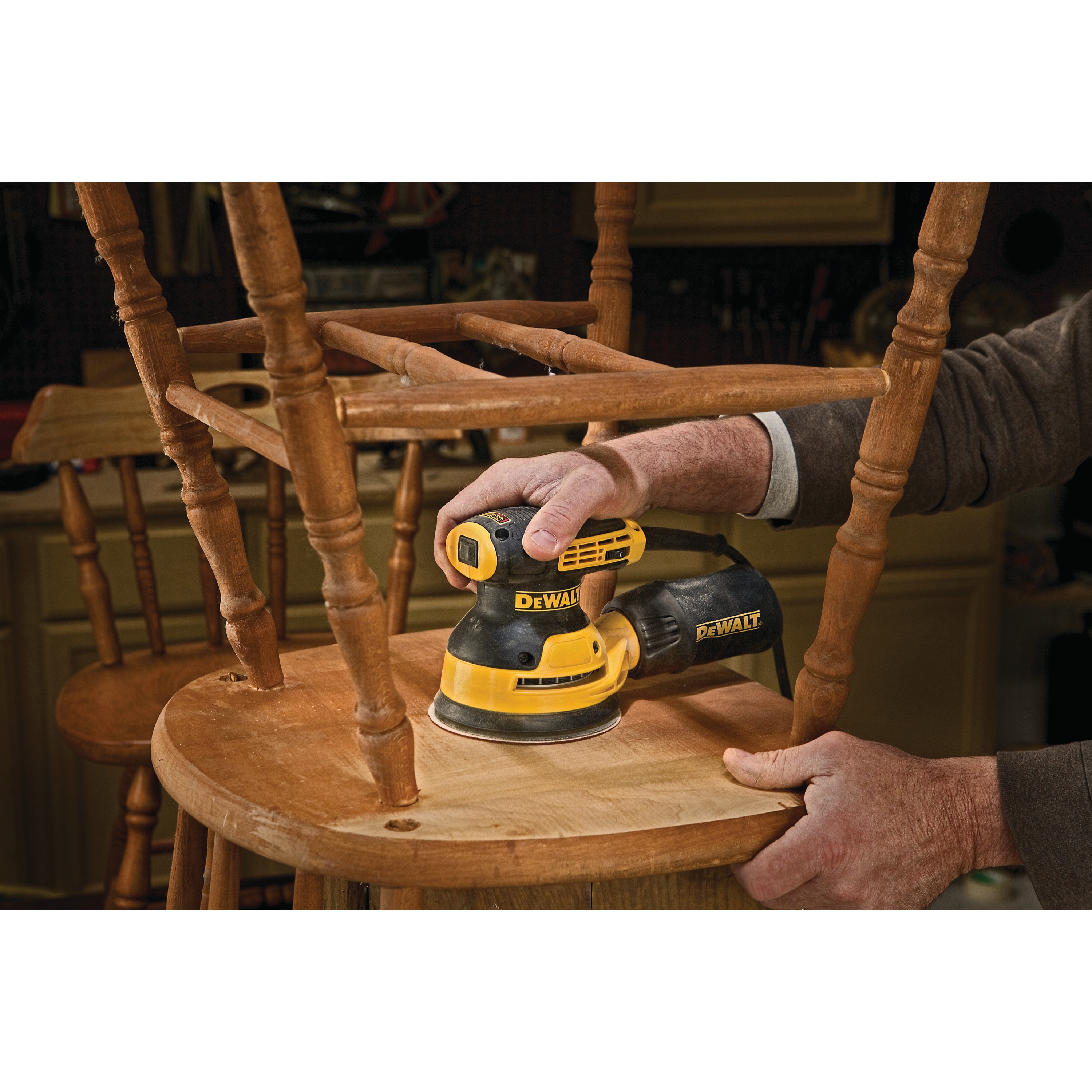 5 inch variable speed random orbit sander with H and L pad in action on bottom of a wooden chair.