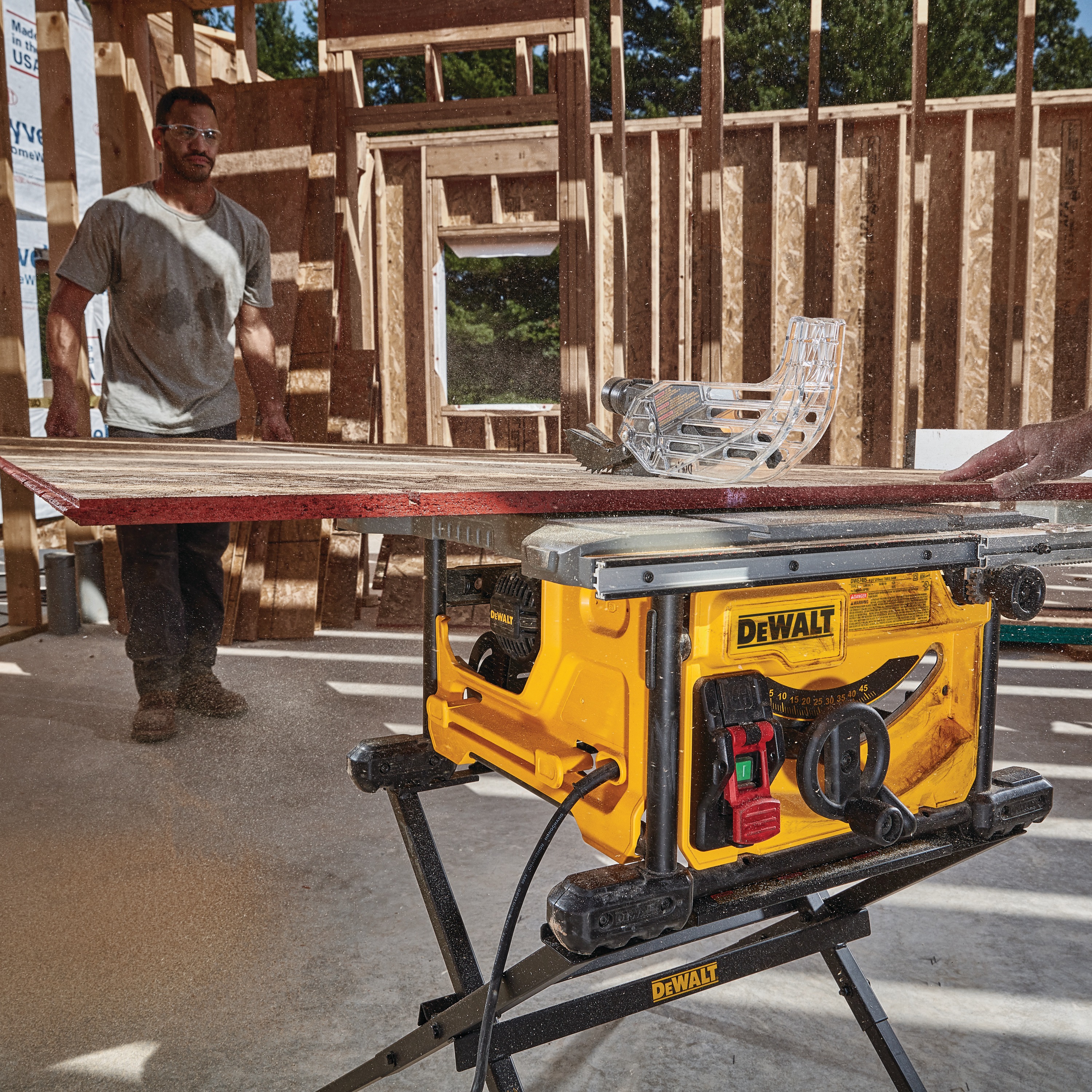 8 and one fourth inch compact table site saw being used to cut a sheet of wood by workers at a worksite.