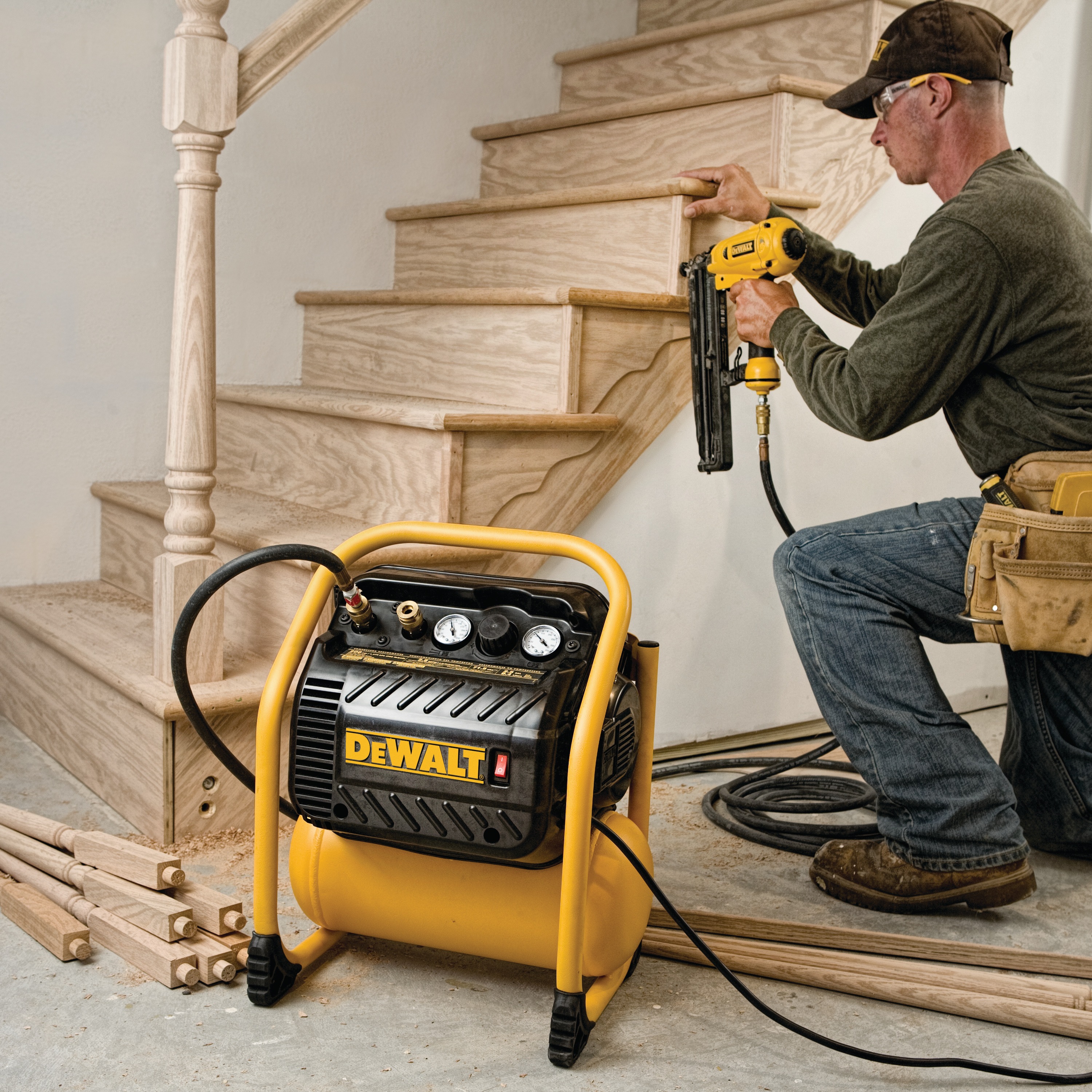 Close up of 200 pounds per square inch Quiet trim compressor being used by a person to drill on wooden stairs.