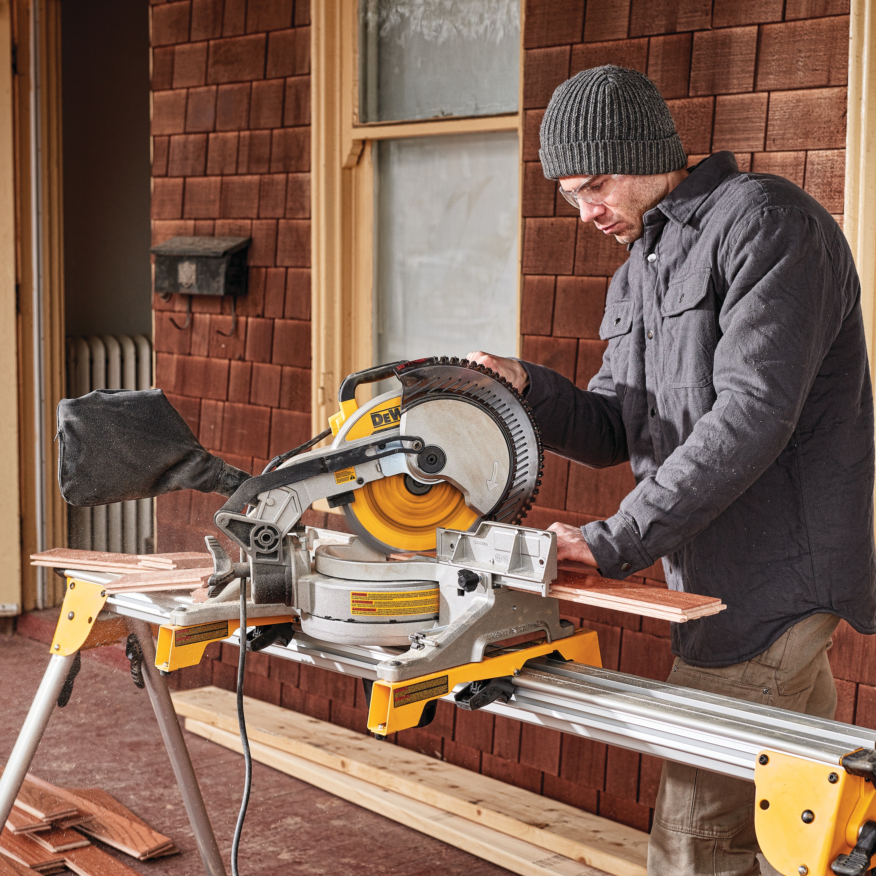 Electric single bevel compound miter saw being used by a person to cut wood.