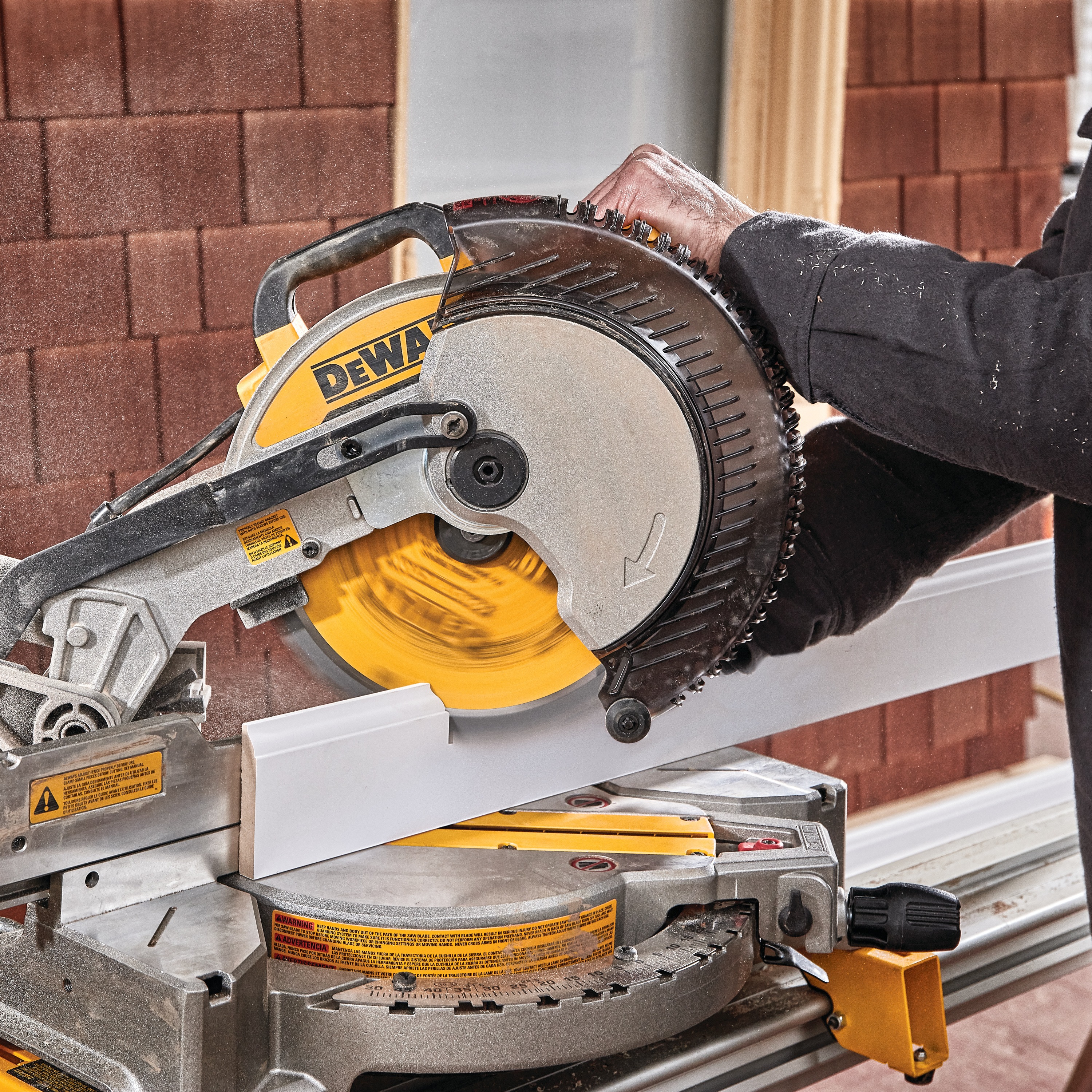 Electric single bevel compound miter saw being used to cut wood.