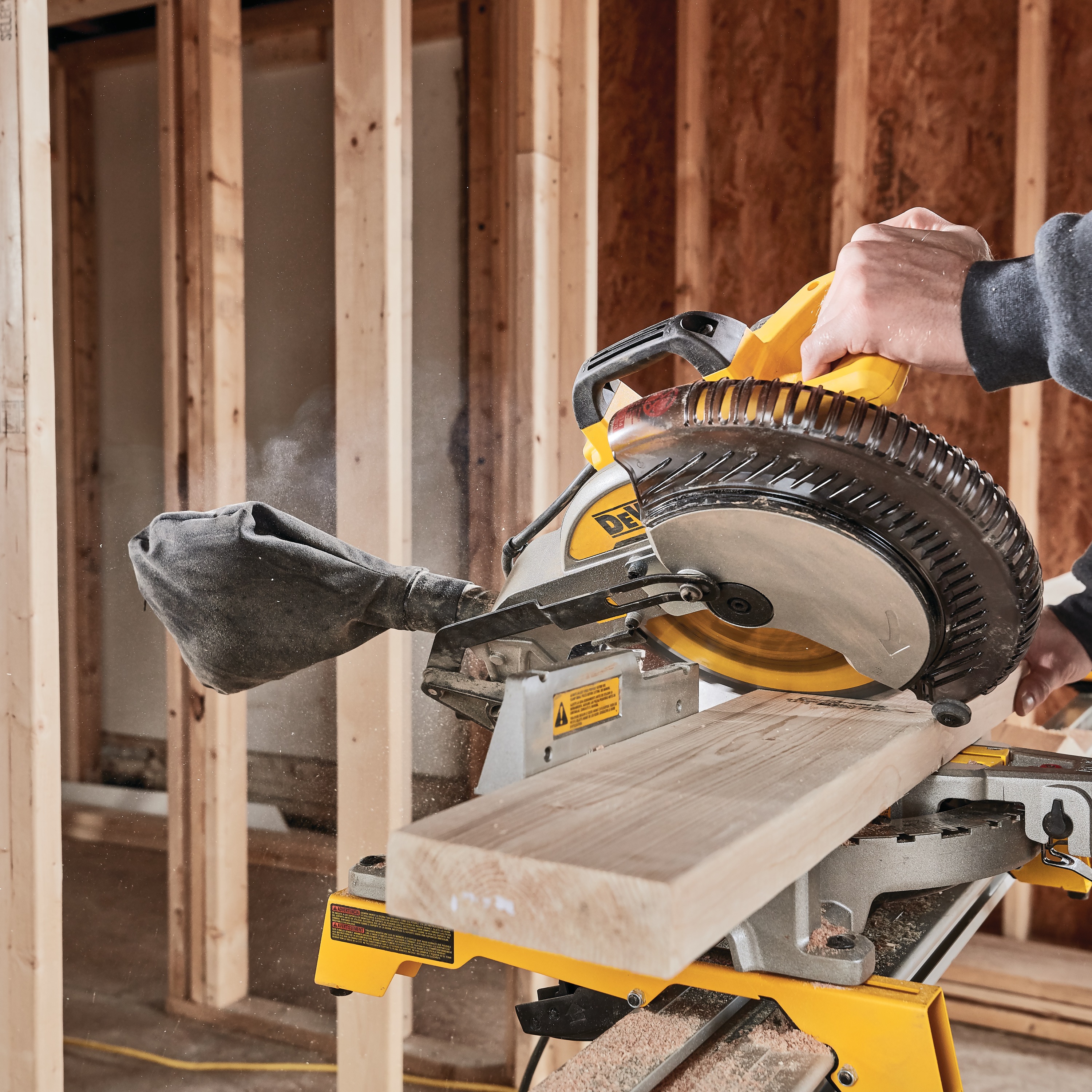 Electric single bevel compound miter saw being used to cut wood.
