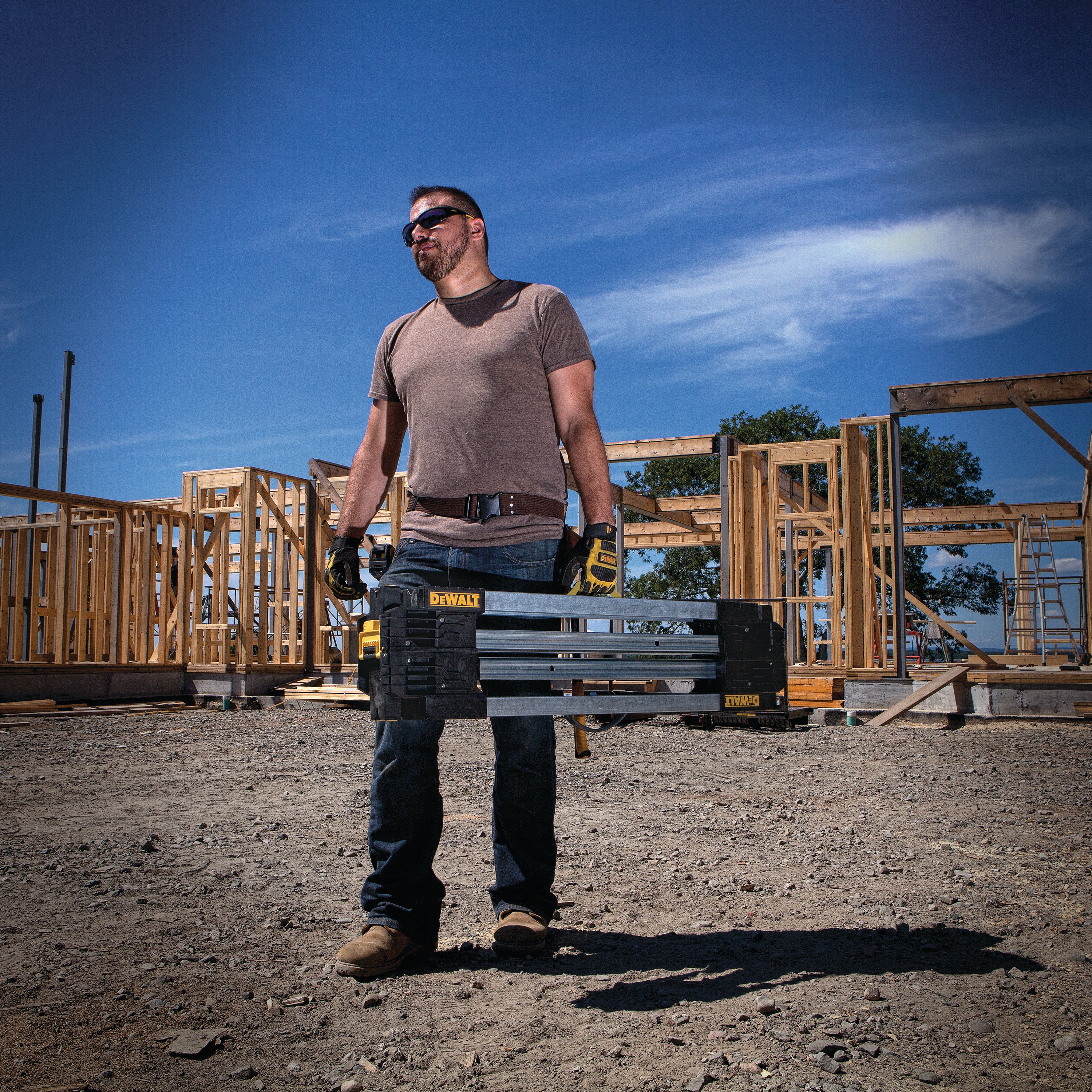 Folded metal folding sawhorse being carried by a person at a worksite.
