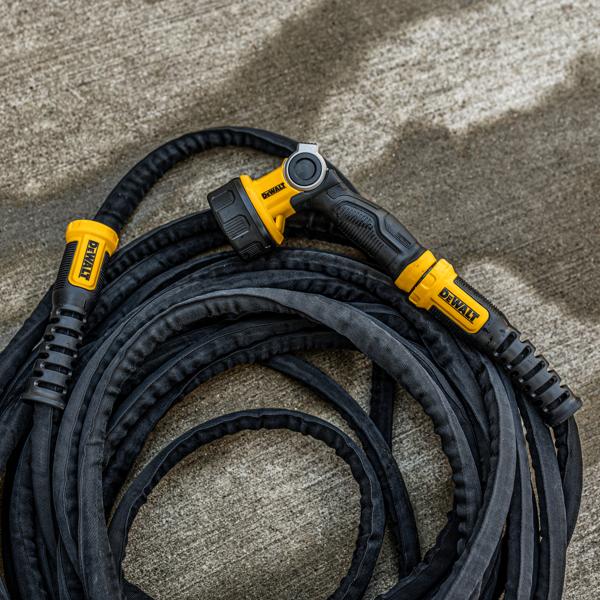 Dewalt Heavy-Duty Fabric Water Hose.Top view in use coiled on concrete and paired with DeWalt Heavy-Duty nozzle.