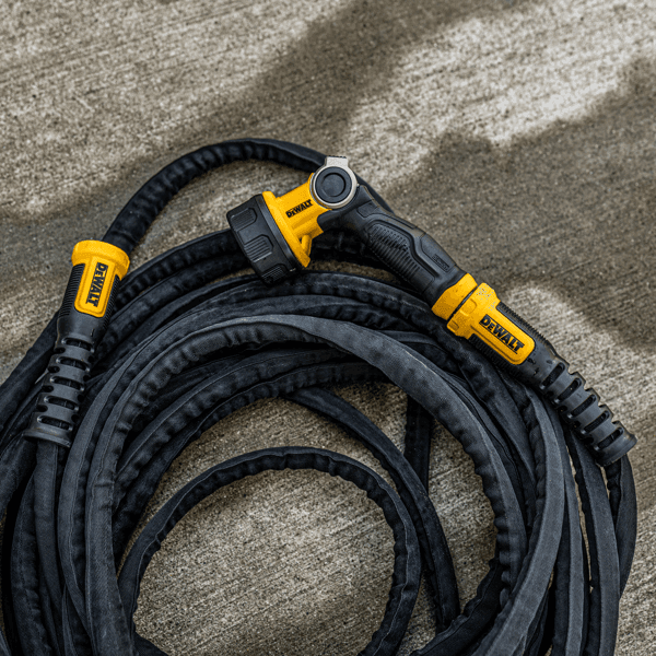 Dewalt Heavy-Duty Fabric Water Hose.Top view in use coiled on concrete and paired with DeWalt Heavy-Duty nozzle.