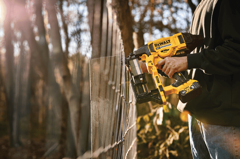 CORDLESS FENCING STAPLER being used on a wooden post by a person