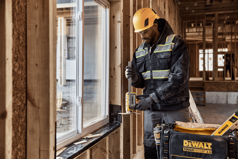Worker holding DEWALT(R) TOUGHSERIES(TM) CONSTRUCTION JACK in front of a window