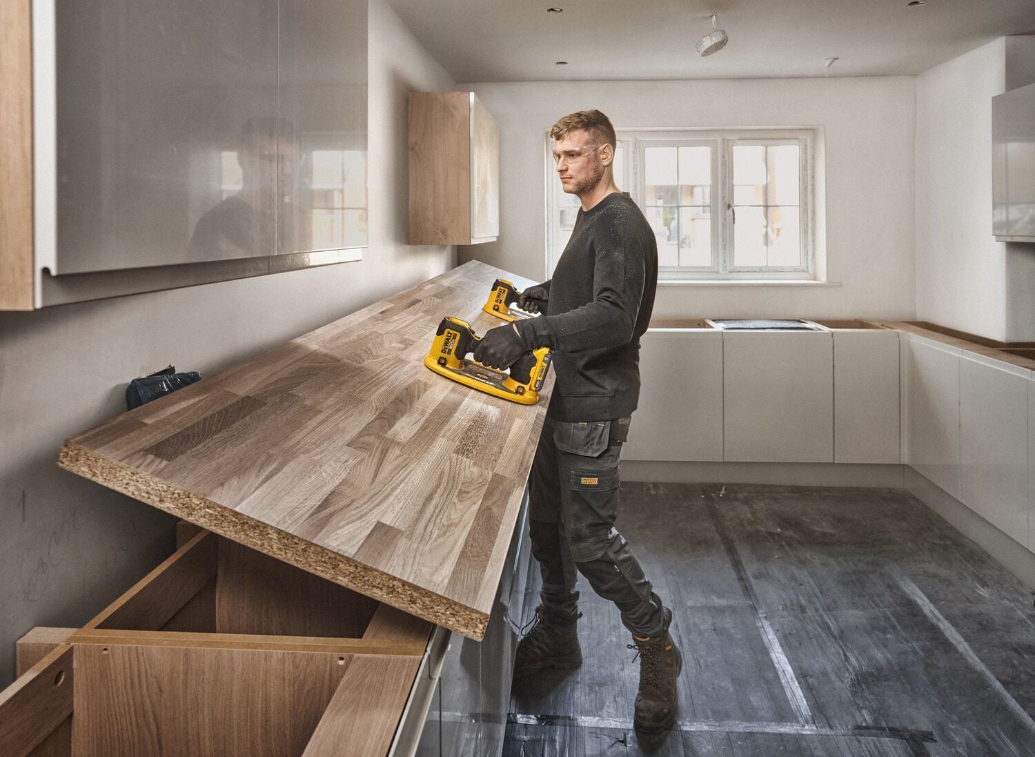 User lifting butcher block with pair of DEWALT 20V MAX Grabo Lifter