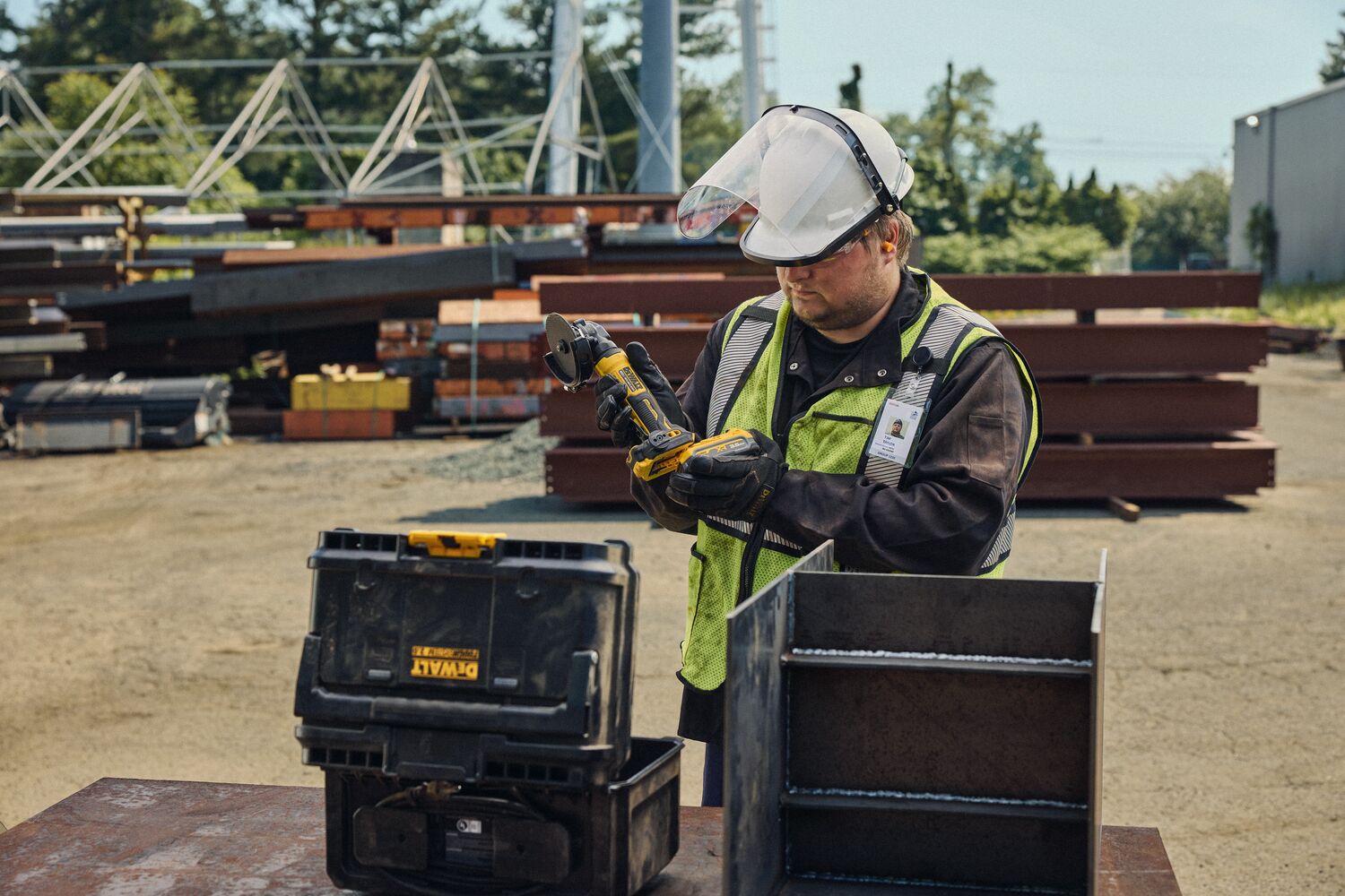User putting battery on ATOMIC™ 20V MAX* 4 in. Angle Grinder on an outdoor industrial site