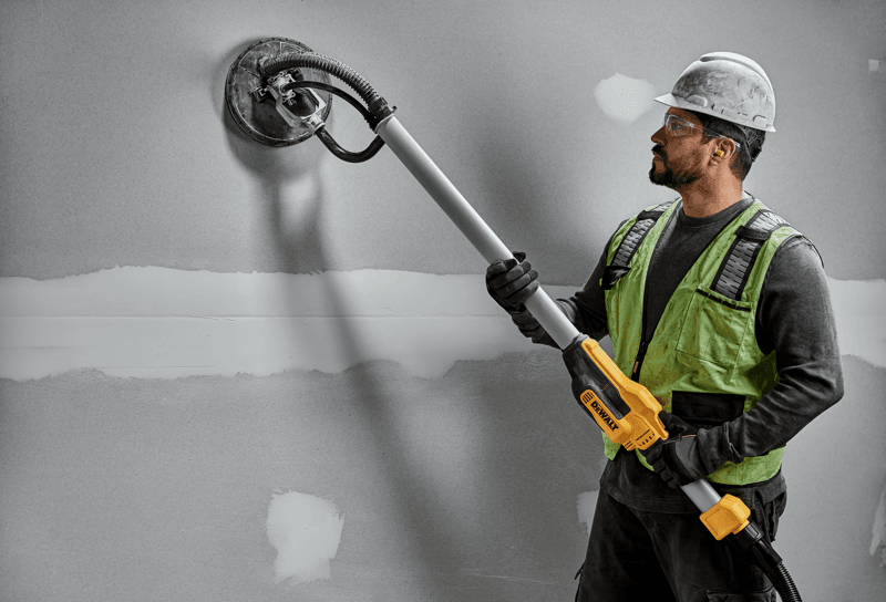 Electric drywall sander polishing wall.
