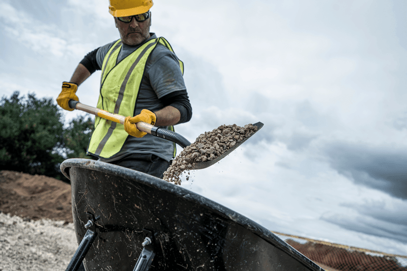 49 inch Wood Handle Transfer Shovel shoveling dirt into wheelbarrow with gray shirt in front view