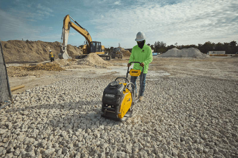 Concrete worker using DEWALT POWERSHIFT plate compactor on stone