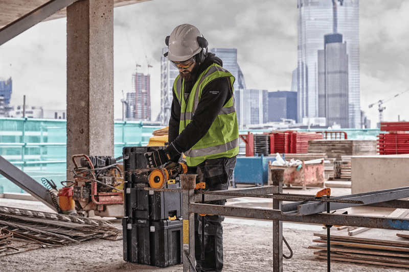 DEWALT DCG418MX1 60V MAX* 4-1/2 in. - 6 in. Grinder being used by a man to cut on a jobsite in the city