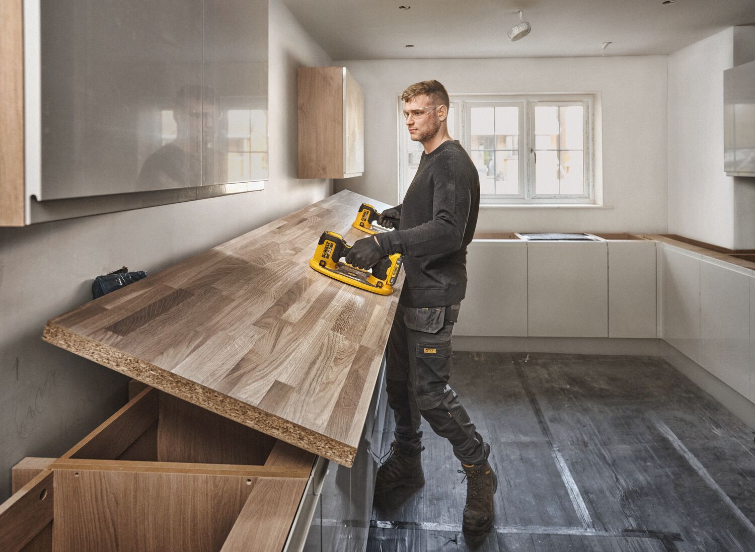 User lifting butcher block with pair of DEWALT 20V MAX Grabo Lifter