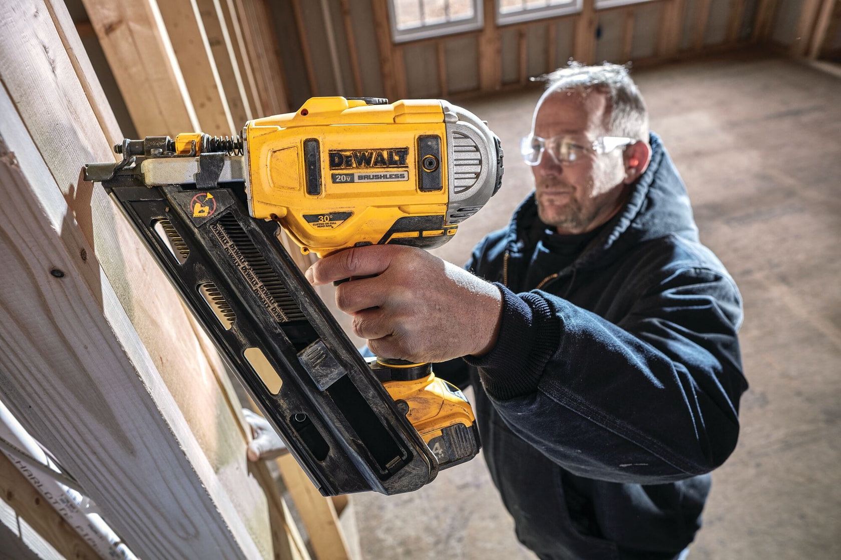 Cordless Paper Collated Framing Nailer in action on a wooden wall by a construction worker at a construction site