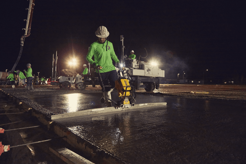 DEWALT POWERSHIFT™ screed smoothing concrete early morning with large board