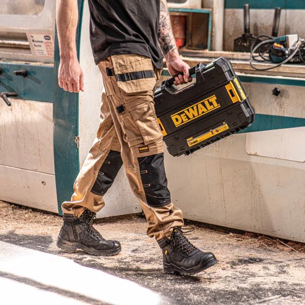 Front view facing right of the DEWALT Protradesman men’s work pants in tan on model on location
