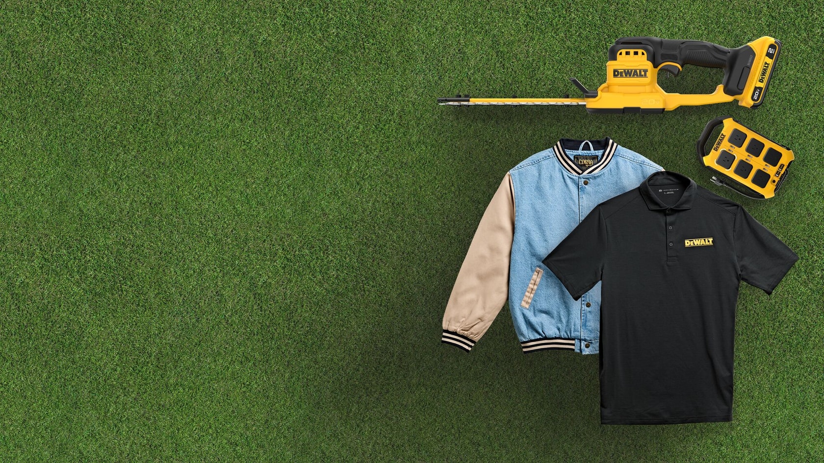 DEWALT jacket, polo shirt, cordless hedge trimmer, and battery on green grass background.