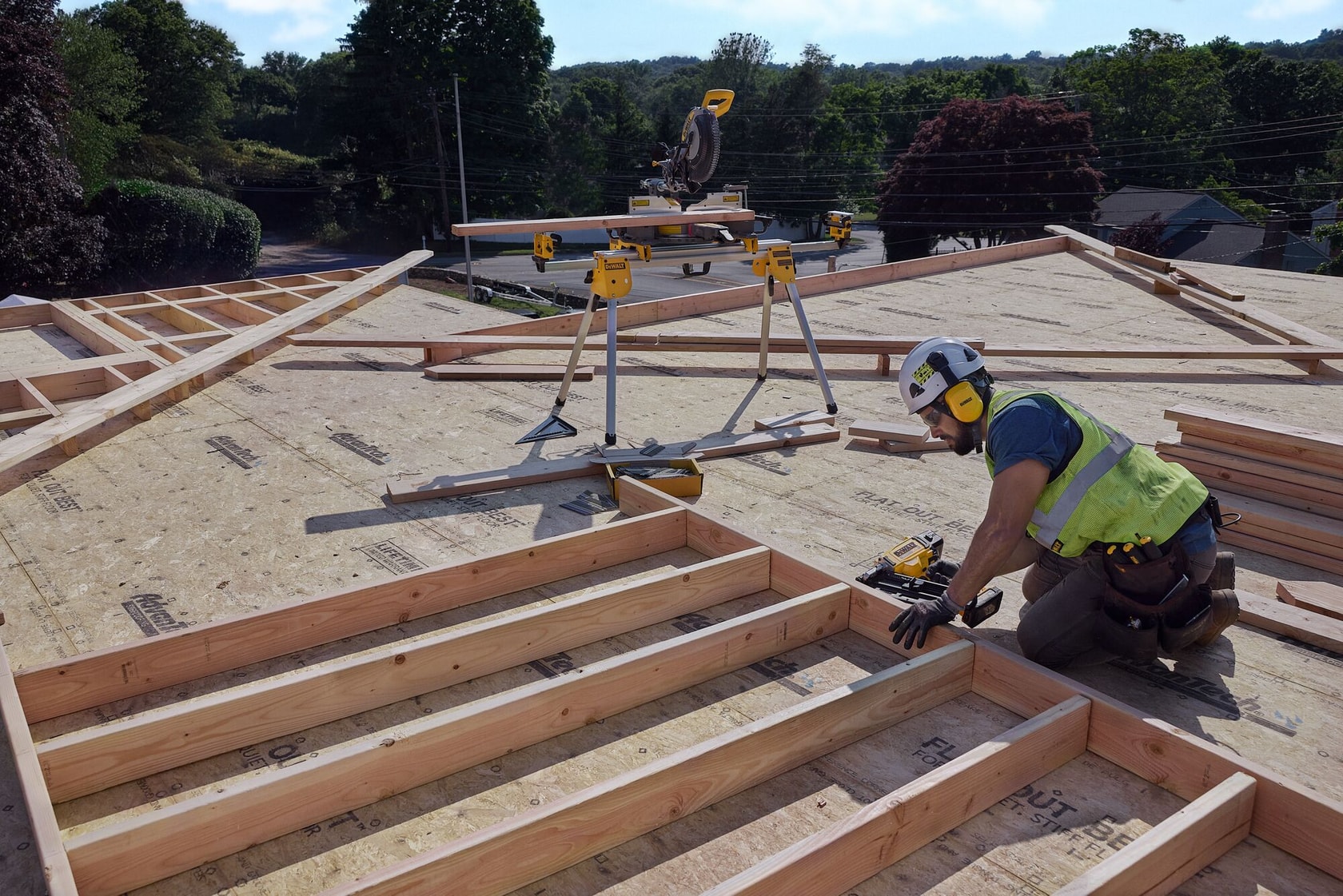 A carpenter uses a nail gun on a frame
