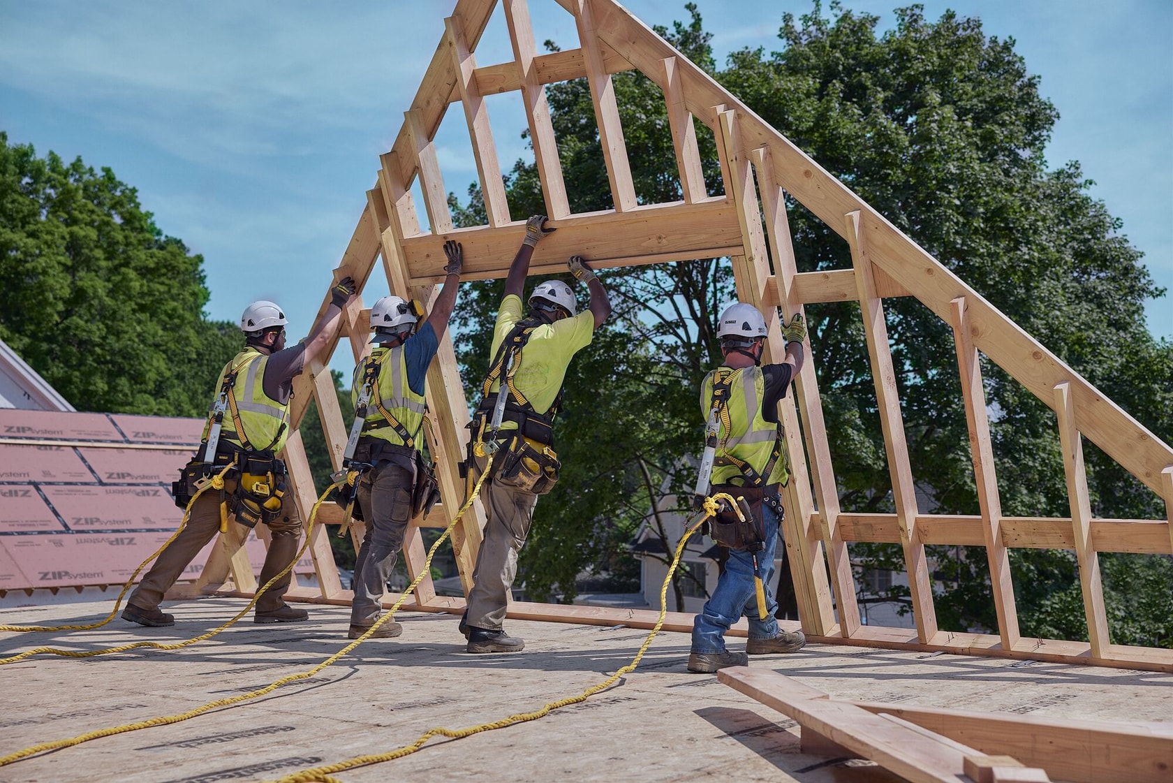 Four carpenters hoist an A-frame