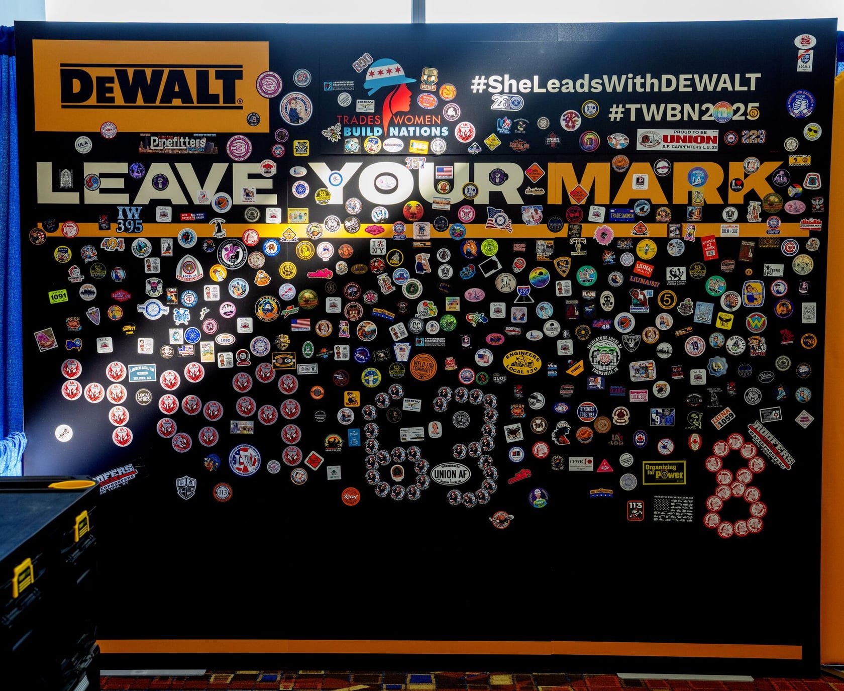 The sticker wall at the DEWALT Booth is covered with stickers from various trade unions and organizations