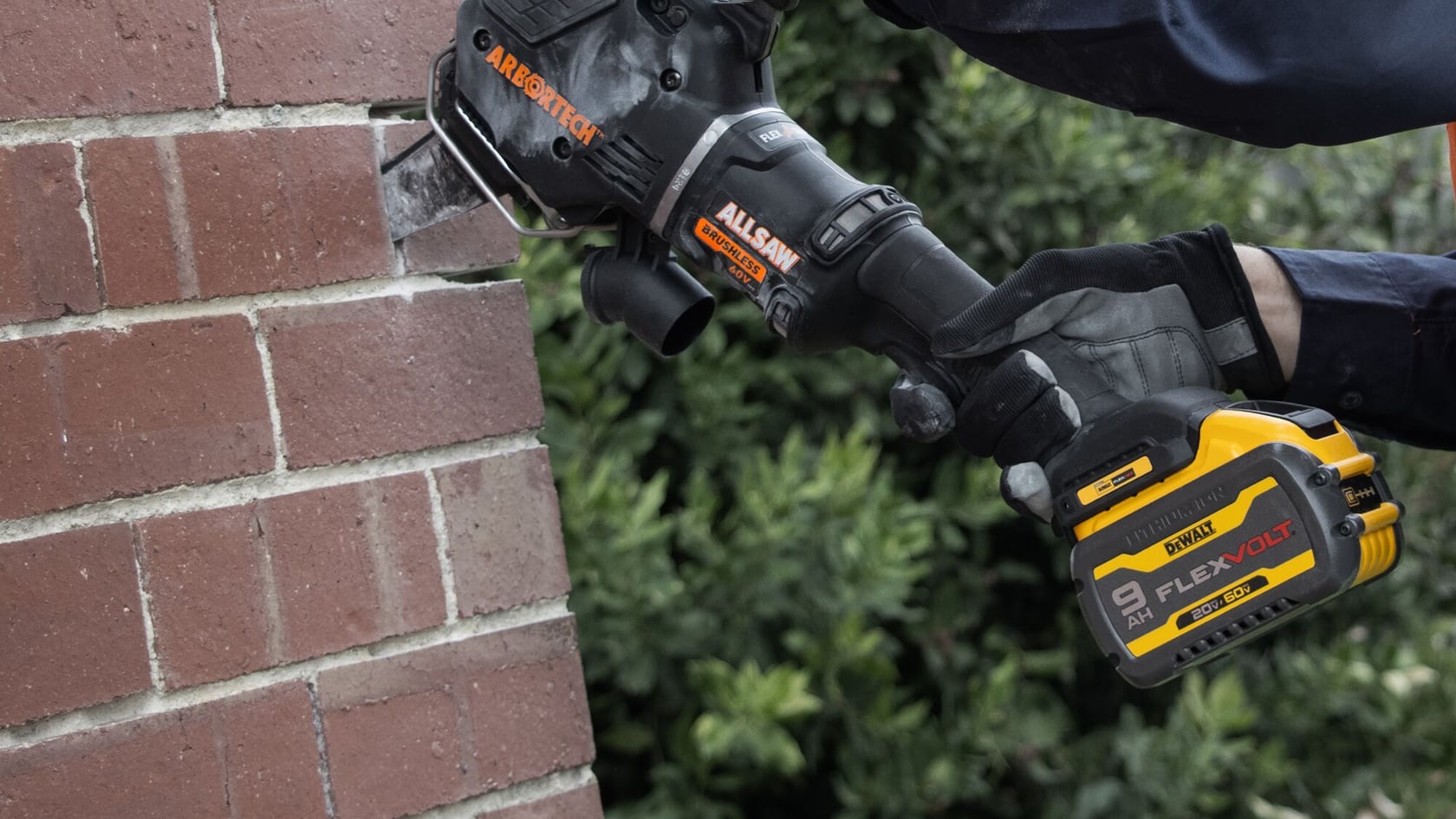 A person using a DEWALT FLEXVOLT power tool to cut into a brick wall, wearing protective gloves. The tool has an Arbortech attachment and is labeled 'ALLSAW'.