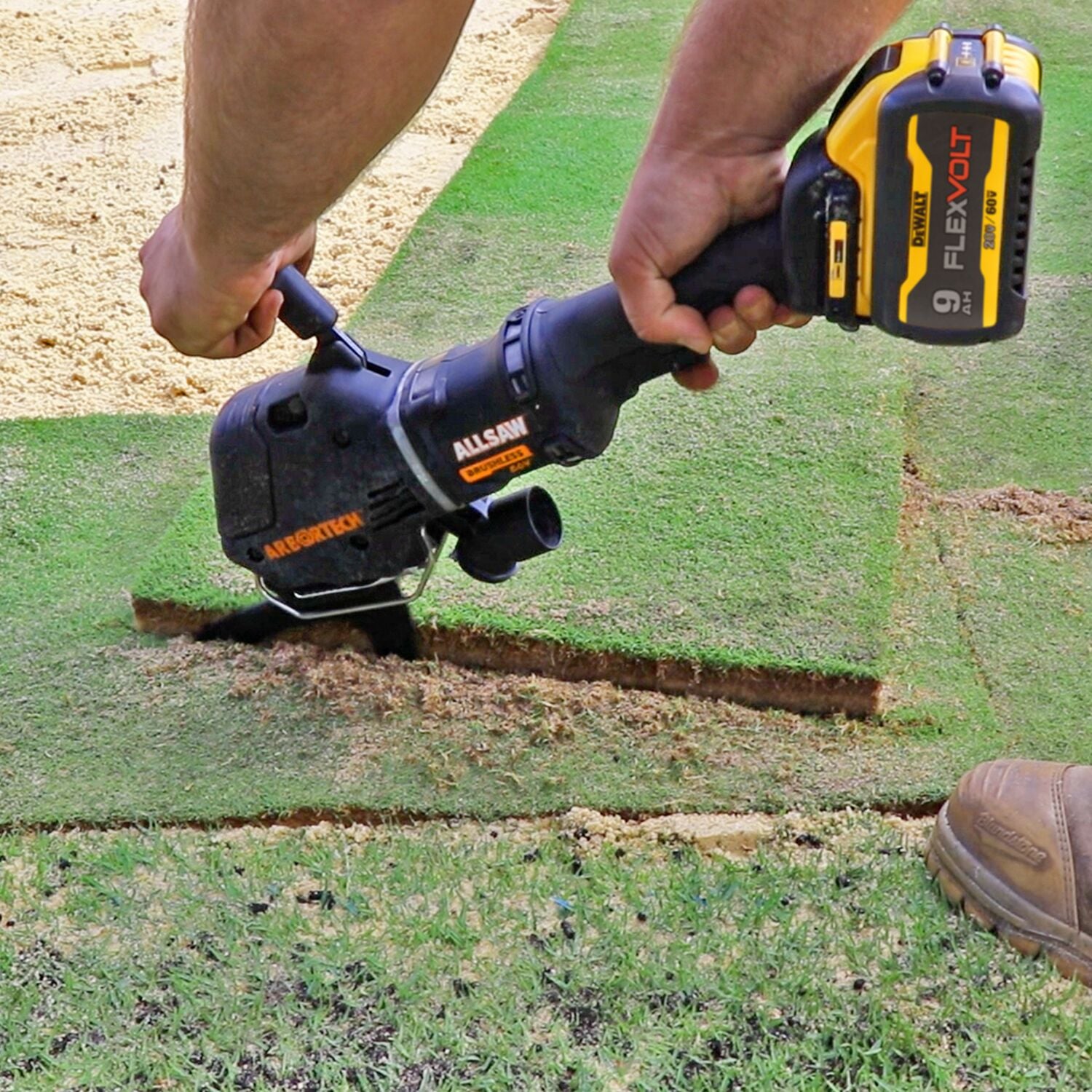 A person uses a DEWALT FLEXVOLT power tool to cut through a piece of turf or sod on a lawn, showing precise and clean edges.
