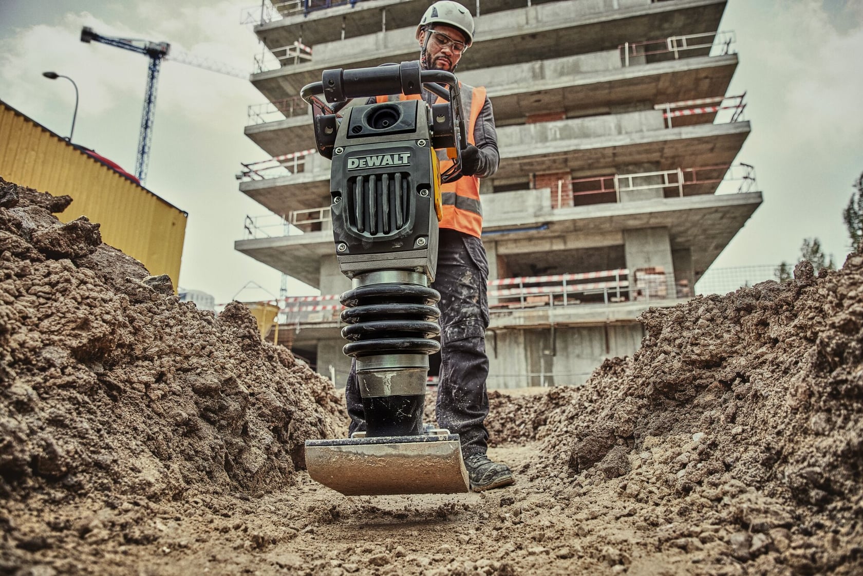 Man operating rammer in dirt trench