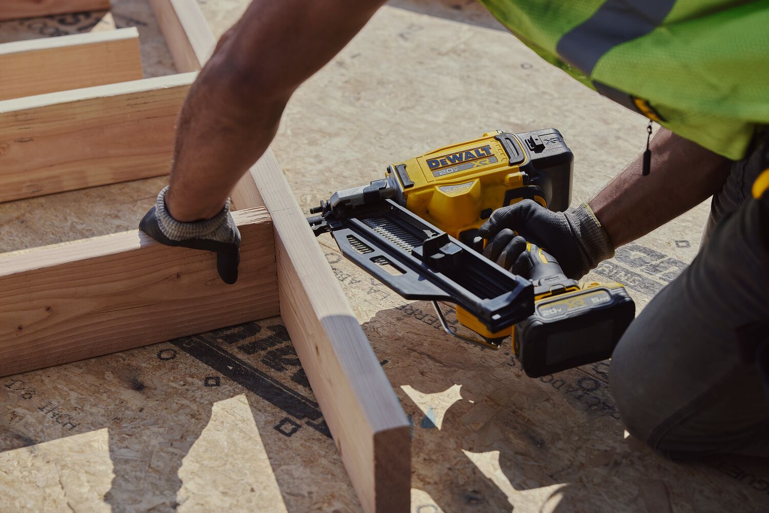 A carpenter uses a nail gun on a frame